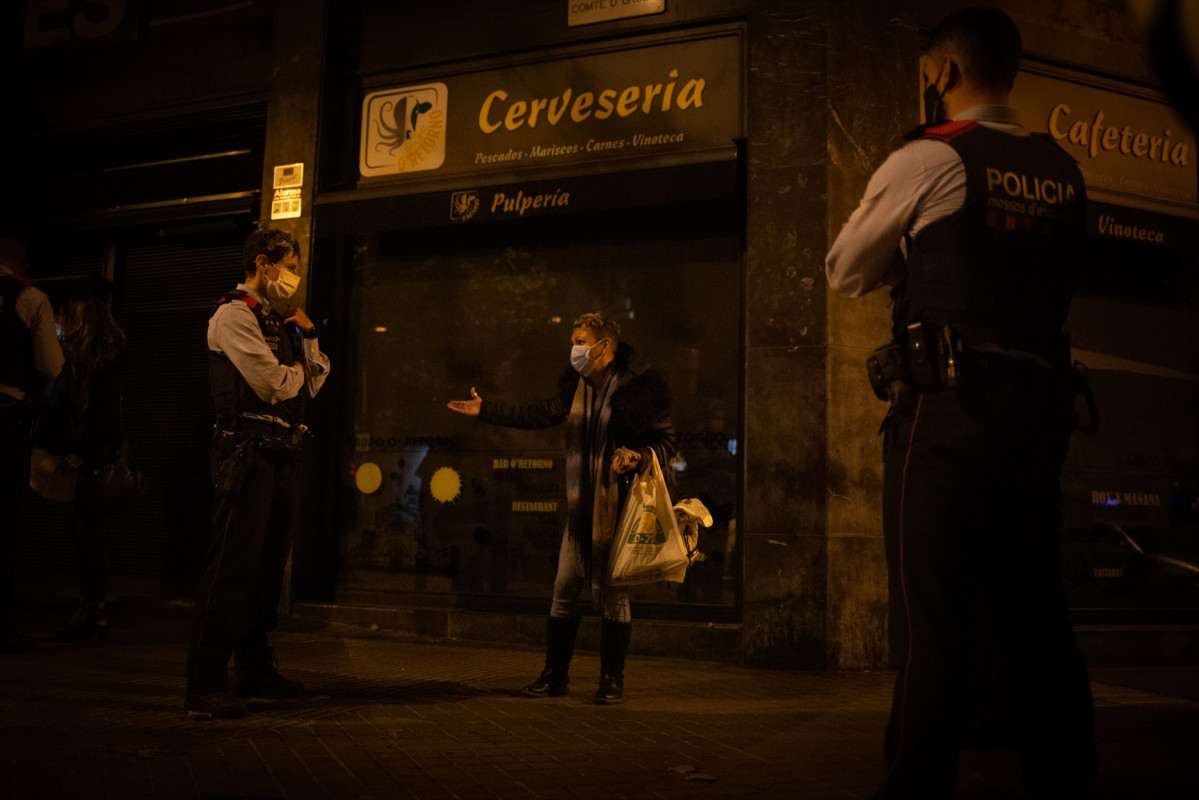Archivo - Varios mossos d'Esquadra paran a una persona durante un control durante el toque de queda impuesto por la crisis sanitaria del Covid-19 desde las 22.00 horas a las 6.00 del día siguiente, en Barcelona, Catalunya, (España), a 6 de noviembre de 20