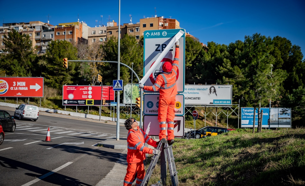 Operaris instal·lant els senyals de trànsit defintius de la ZBE Rondes BCN en el branc de la sortida 14 Besòs de la Ronda de Dalt, a L'Hospitalet de Llobregat