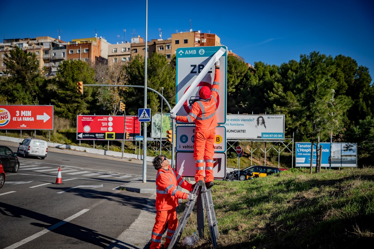 Operaris instal·lant els senyals de trànsit defintius de la ZBE Rondes BCN en el branc de la sortida 14 Besòs de la Ronda de Dalt, a L'Hospitalet de Llobregat