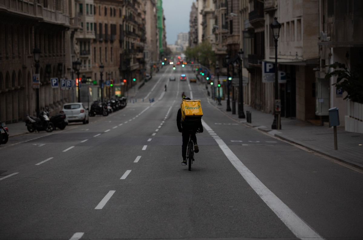 Un trabajador de Glovo en bicicleta por una calle de Barcelona, prácticamente vacía durante el estado de alarma en el país a consecuencia del coronavirus, en Barcelona/Catalunya (España) a 23 de m