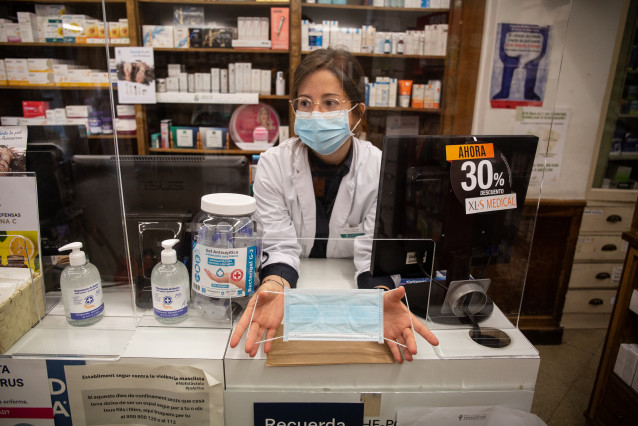 Una farmacéutica muestra una de las mascarillas que la Generalitat ha comenzado hoy a repartir a la población dentro de una primera tanda de 1,5 millones de unidades.