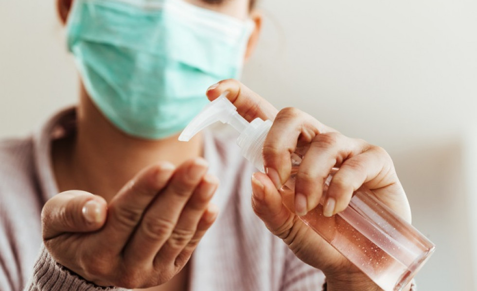 Mujer con mascarilla y gel hidroalcohólico.