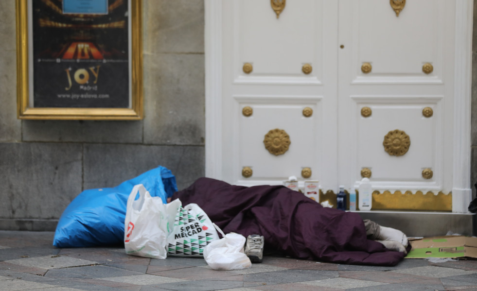 Una persona sin hogar duerme en la calle Arenal de Madrid.