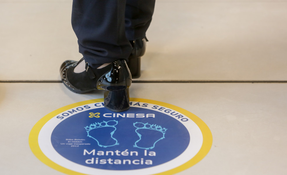 Archivo - Una persona pisa uno de los carteles indicativos para mantener la distancia de seguridad instalados en el cine Cinesa LUXE Xanadú, situado en la localidad madrileña de Arroyomolinos