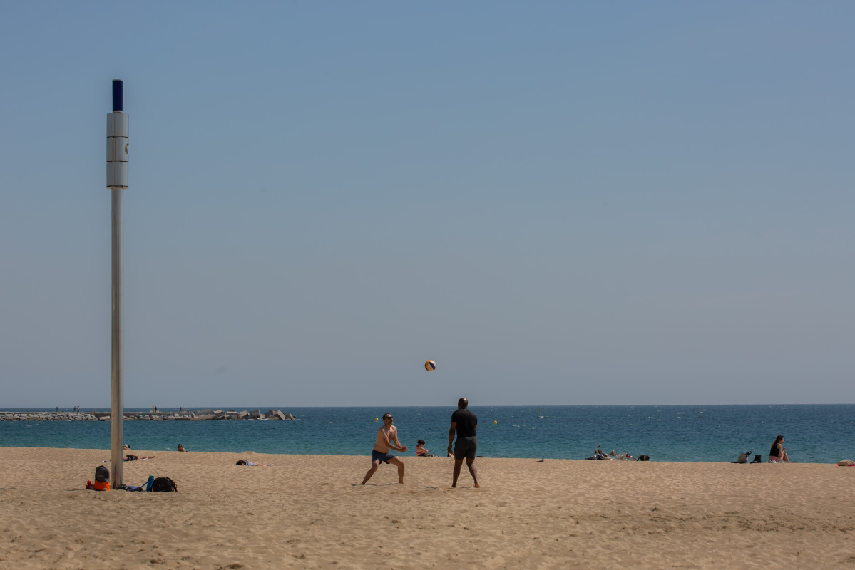 Dos hombres juegan al voleibol en la playa del Bogotell el día de la presentación del protocolo para el control del aforo de playas, a 6 de mayo de 2021, en Barcelona, Catalunya, (España).