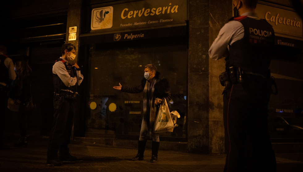 Archivo - Varios mossos d'Esquadra paran a una persona durante un control durante el toque de queda impuesto por la crisis sanitaria del Covid-19 desde las 22.00 horas a las 6.00 del día siguiente, e