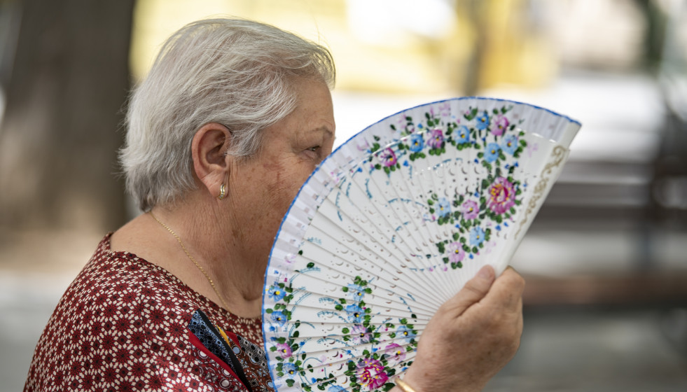 Una mujer agita su abanico en una plaza para combatir el calor.