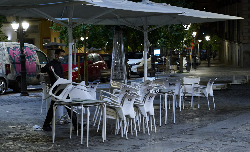 Archivo - Una persona recoge la terraza de una cafetería en Madrid durante la primera jornada en la que se permite el cierre a la 01.00 en hostelería y recintos culturales, a 31 de mayo de 2021, en 