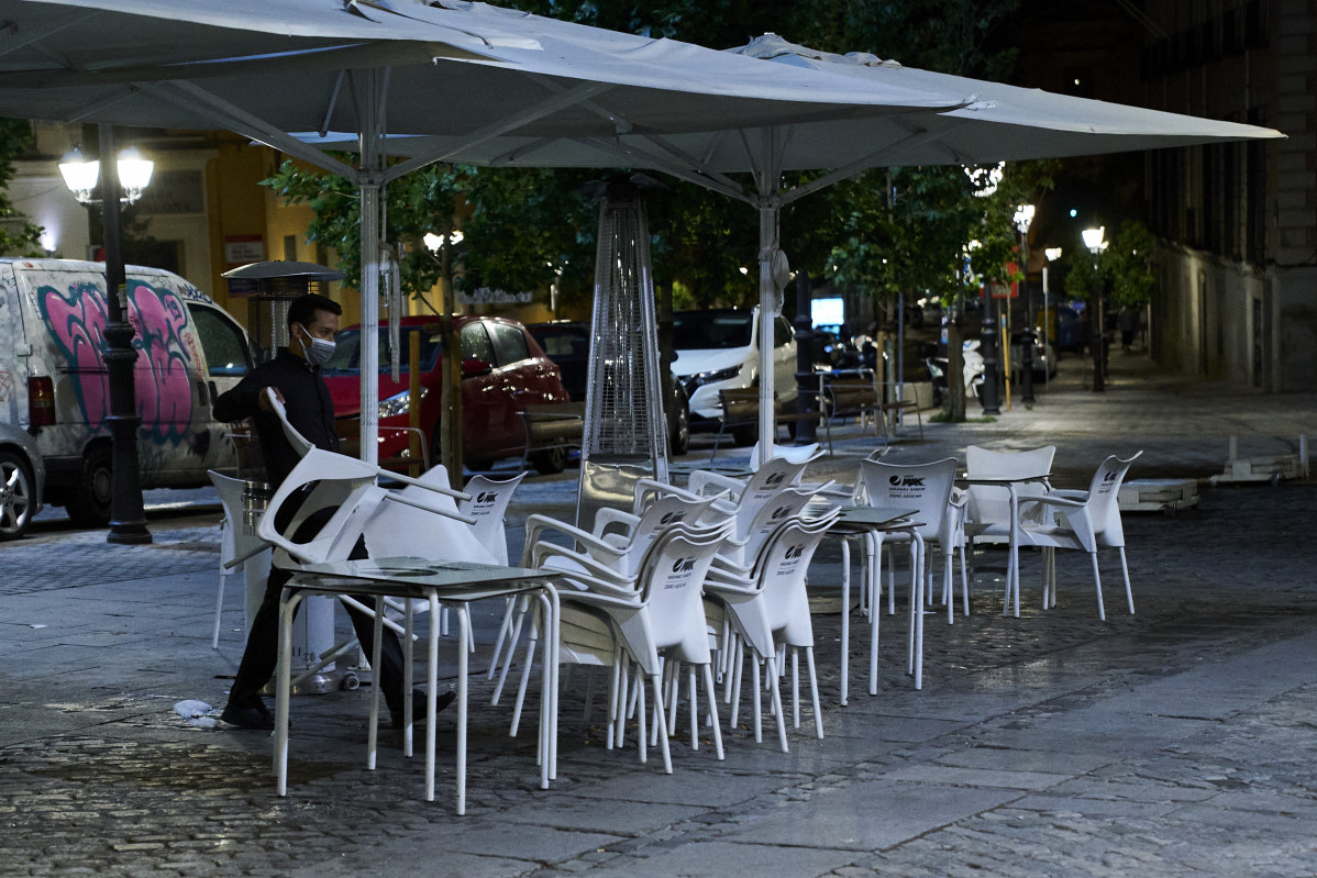 Archivo - Una persona recoge la terraza de una cafetería en Madrid durante la primera jornada en la que se permite el cierre a la 01.00 en hostelería y recintos culturales, a 31 de mayo de 2021, en Madrid (España). La ampliación de horarios hasta la 01.00
