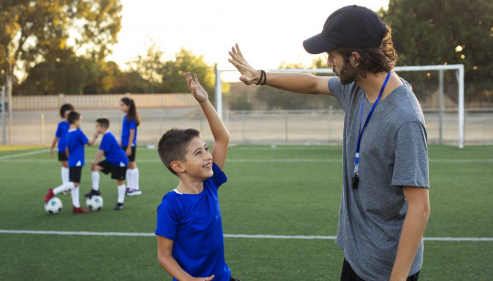 Entrenador futbol felicitando vista lateral nino 1024x683 1