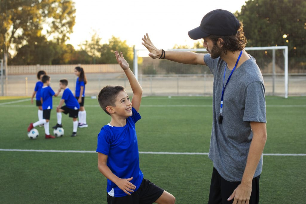 Entrenador futbol felicitando vista lateral nino 1024x683 1