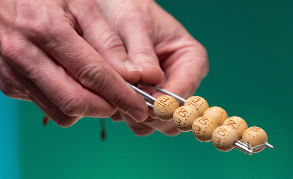 Un hombre enseña las bolas con la cantidad de dinero de uno de los premios al inicio del Sorteo Extraordinario de la Lotería de Navidad 2023 en el Teatro Real de Madrid, a 22 de diciembre de 2023, e