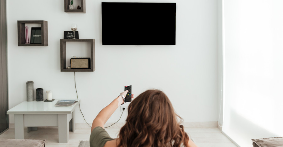 Back view casual woman sitting sofa watching tv home