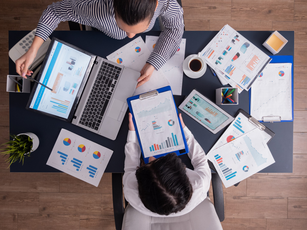 Vista superior del gerente y el empleado que trabajan en equipo en la oficina de negocios mirando graficos en la pantalla de la computadora portatil