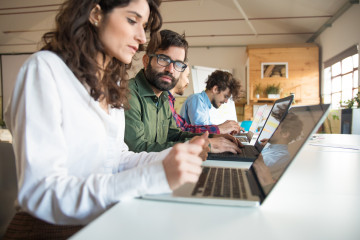 Companeros de trabajo serios con laptops discutiendo proyecto
