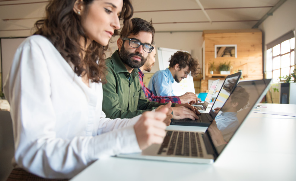Companeros de trabajo serios con laptops discutiendo proyecto