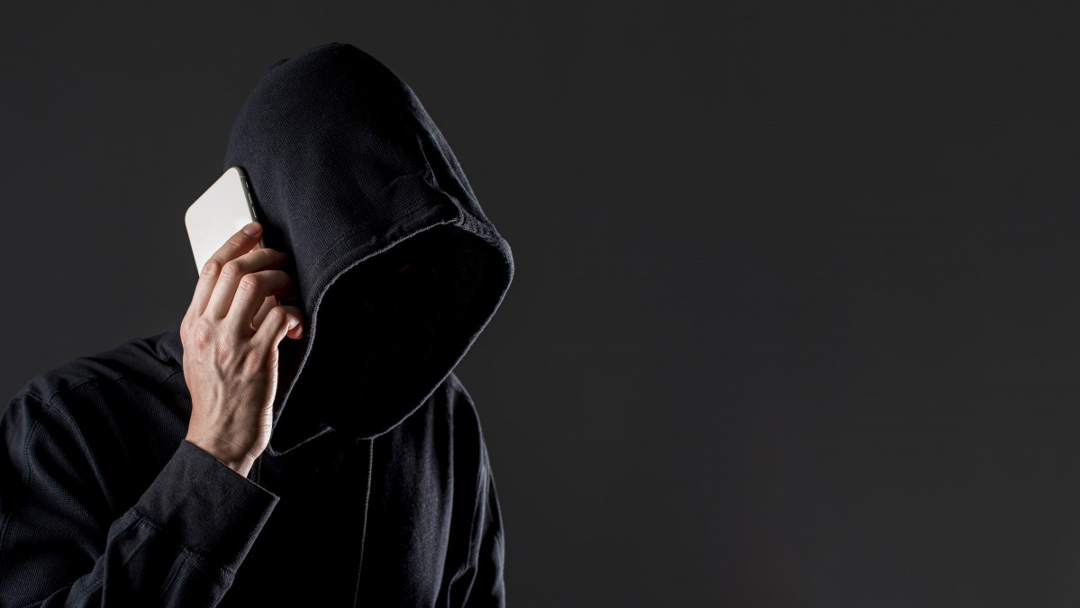 Vista lateral del pirata informatico masculino hablando por telefono inteligente con espacio de copia