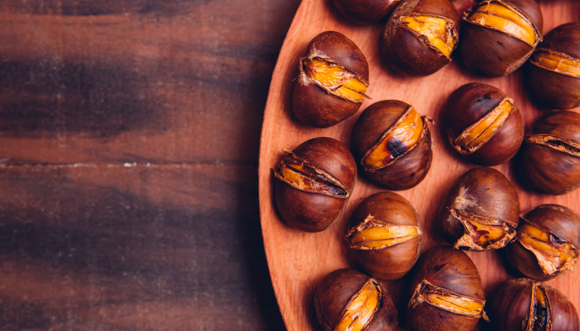 Castanas en un plato de madera sobre una mesa de madera oscura