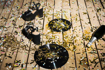 Discos de vinilo zapatos de mujer y botella de bebida entre confeti