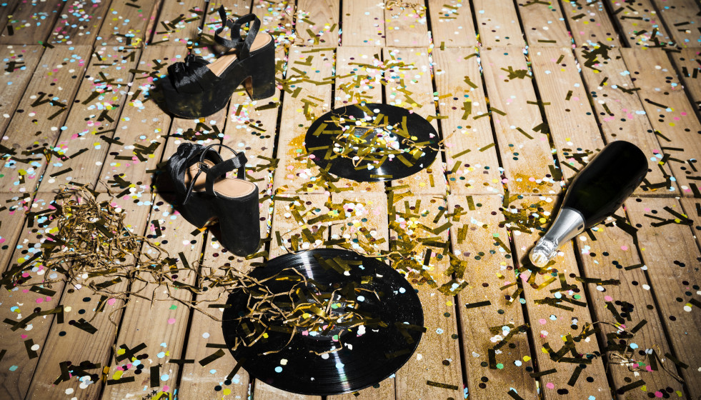 Discos de vinilo zapatos de mujer y botella de bebida entre confeti