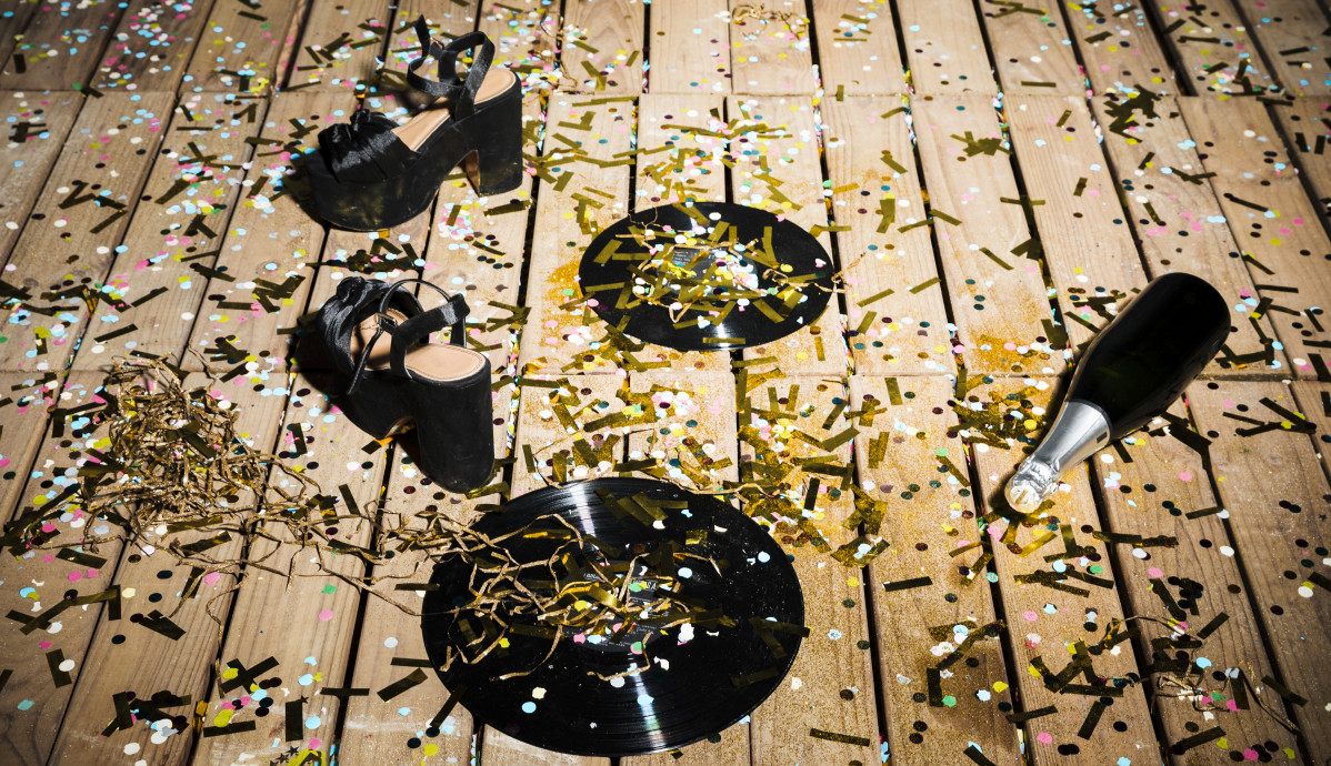 Discos de vinilo zapatos de mujer y botella de bebida entre confeti