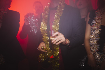 Fiesta de ano nuevo en discoteca con hombre sujetando vaso