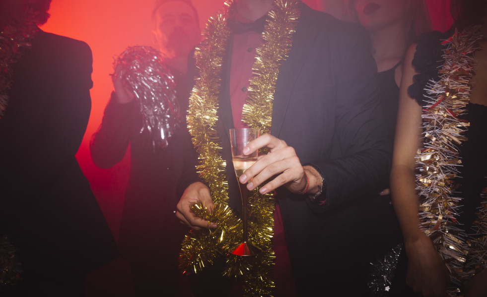 Fiesta de ano nuevo en discoteca con hombre sujetando vaso
