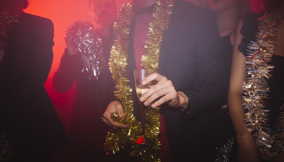 Fiesta de ano nuevo en discoteca con hombre sujetando vaso