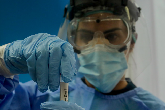 Una trabajadora sanitaria sostiene una probeta con una prueba PCR (Archivo)