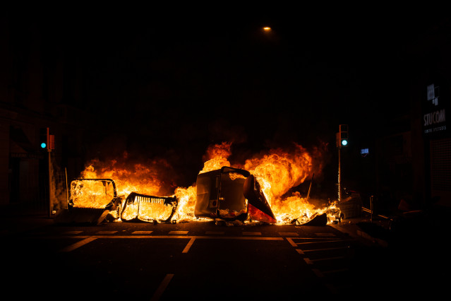 Un contenedor incendiado por los manifestantes que apoyan a Pablo Hasel durante los disturbios en Barcelona (España), a 17 de febrero de 2021. El rapero Pablo Hasel ingresó la mañana de ayer martes en el centro penitenciario de Ponent, en Lleida, tras ser