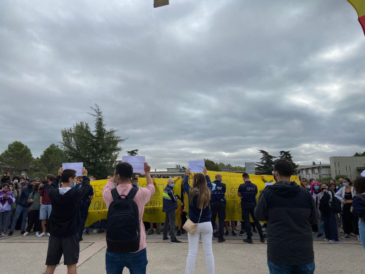 Miembros de la organización estudiantil 'S'ha acabat!' exhiben carteles frente a una concentración ante su carpa informativa en el campus de la UAB en Bellaterra (Barcelona)